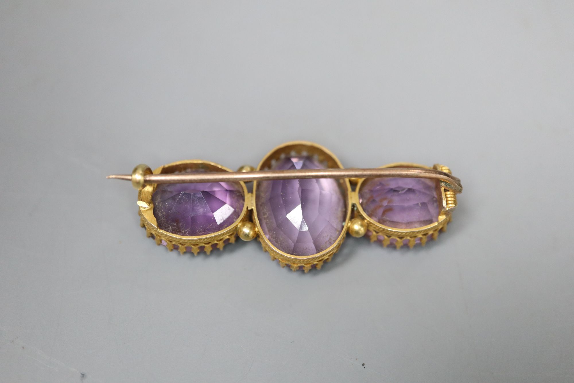 A Victorian yellow metal and three stone amethyst bar brooch, 4.25cm, later cased